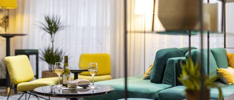 Una sala de estar moderna con una mesa redonda, sillas amarillas y verdes, y un sofá.