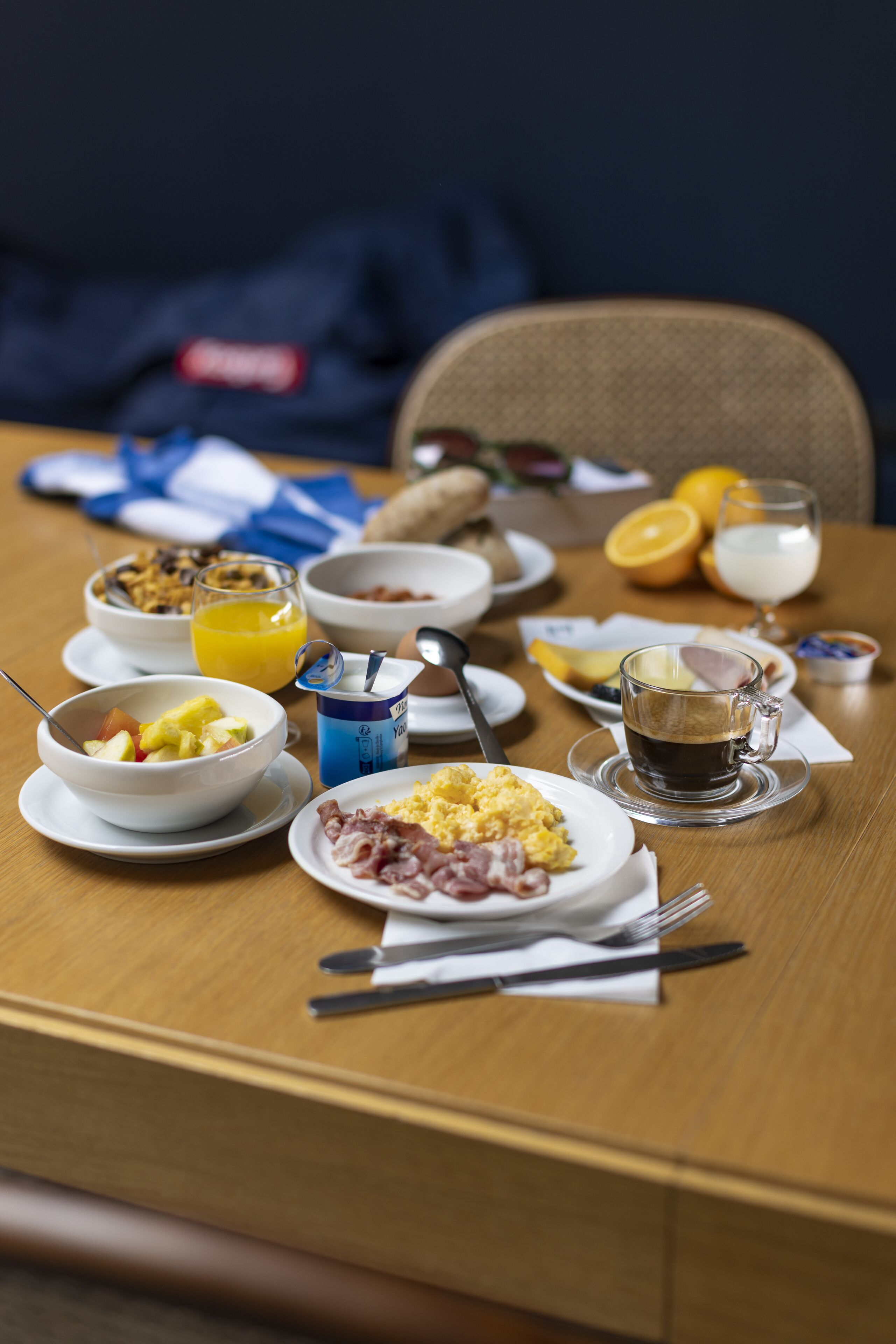 A breakfast table with various dishes including eggs, bacon, and orange juice.