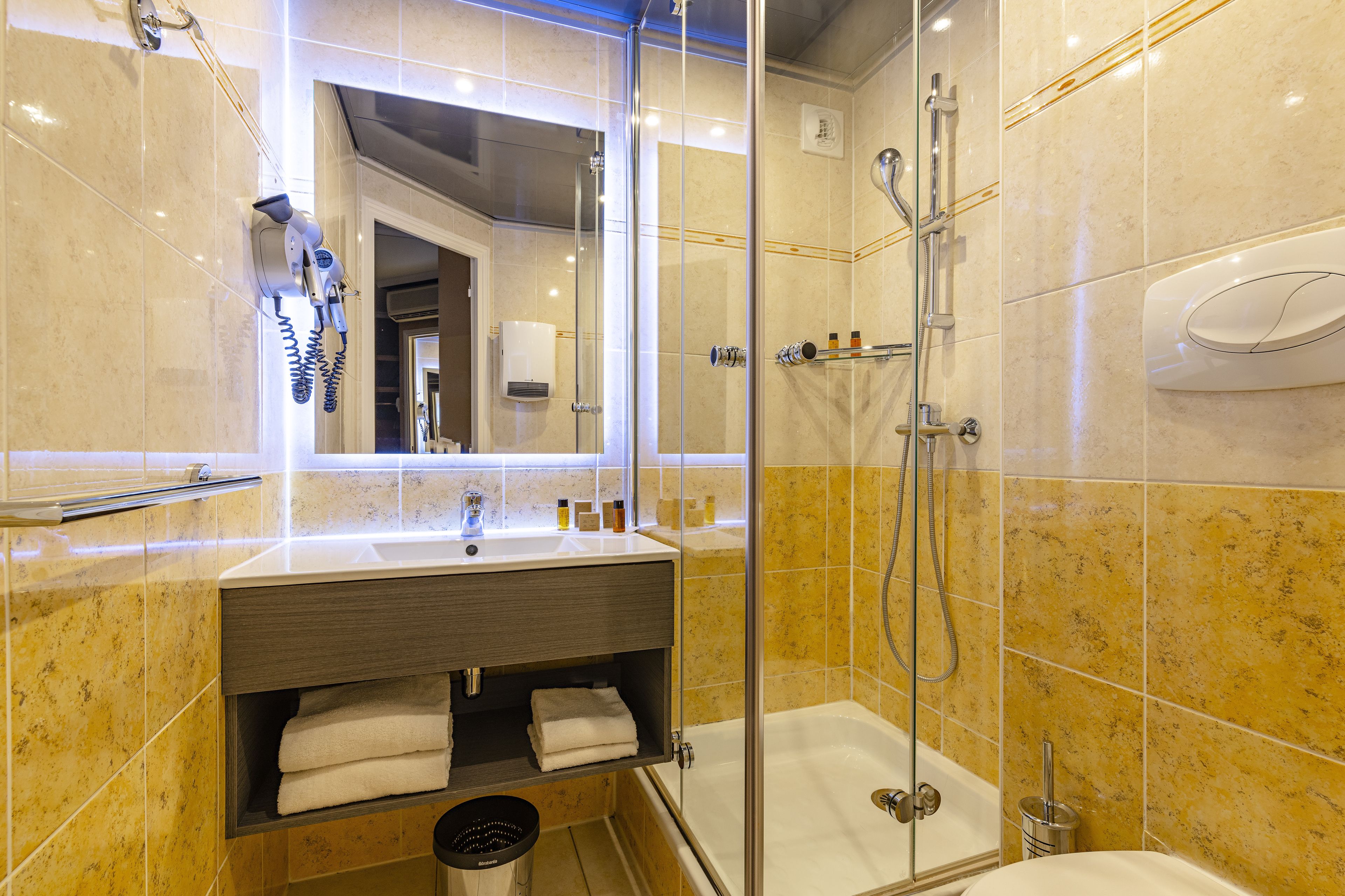 A modern bathroom with a glass-enclosed shower, a vanity with a mirror, and a bathtub.