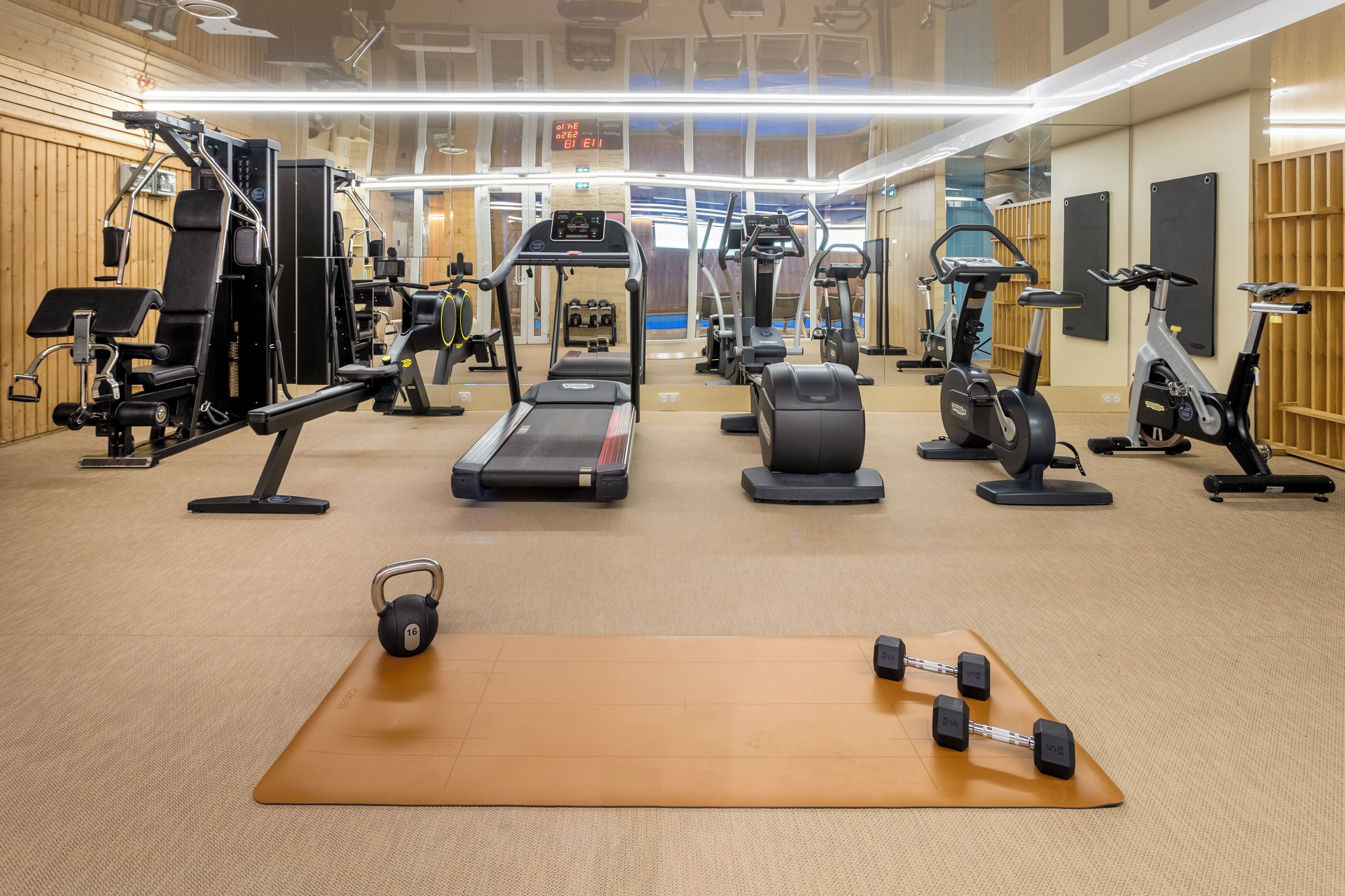 A gym with various exercise equipment including treadmills, stationary bikes, and free weights.