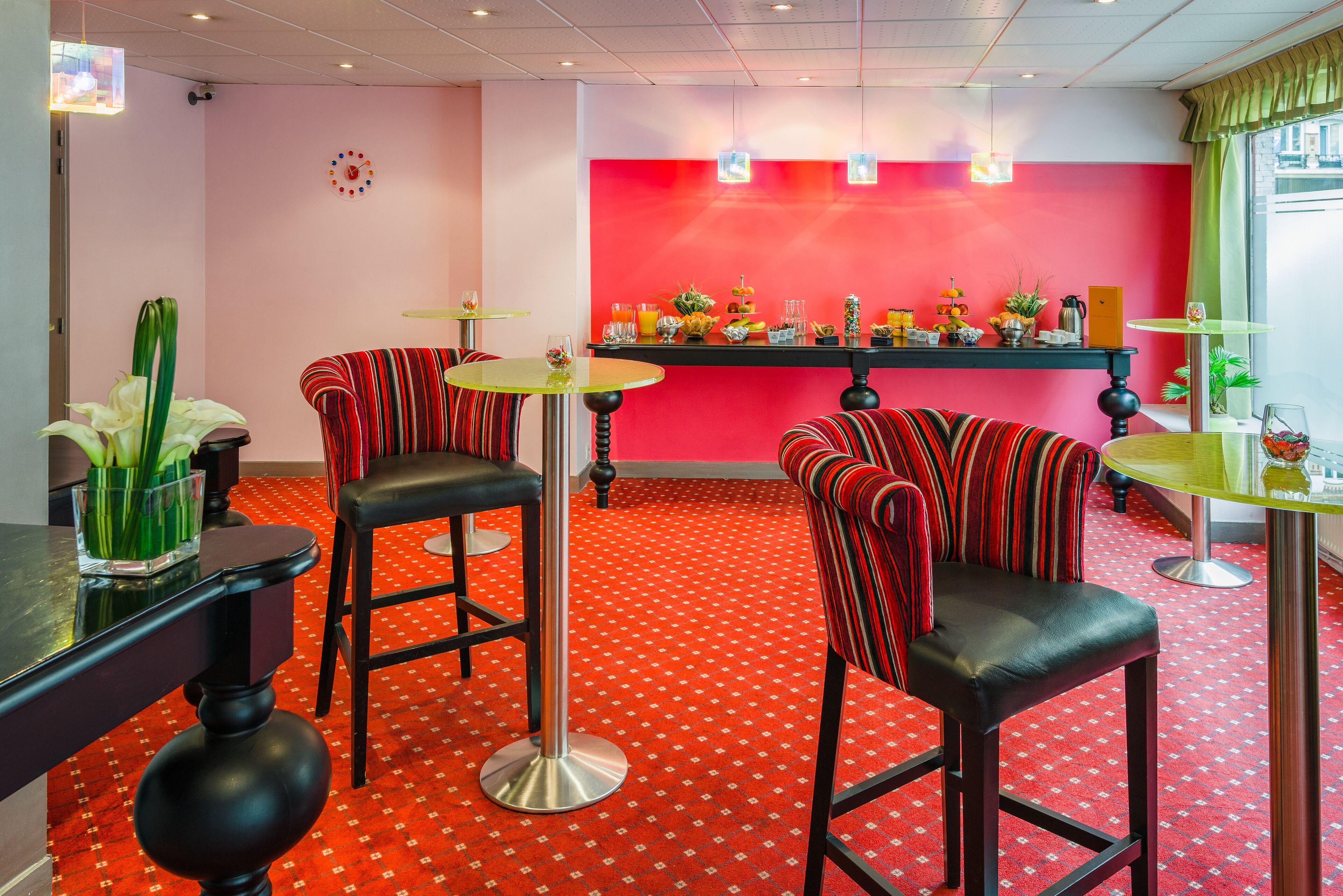 A vibrant bar area with red and black striped barstools, a red patterned carpet, and a bar counter with various items.