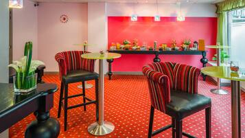 A vibrant bar area with red and black striped barstools, a red patterned carpet, and a bar counter with various items.