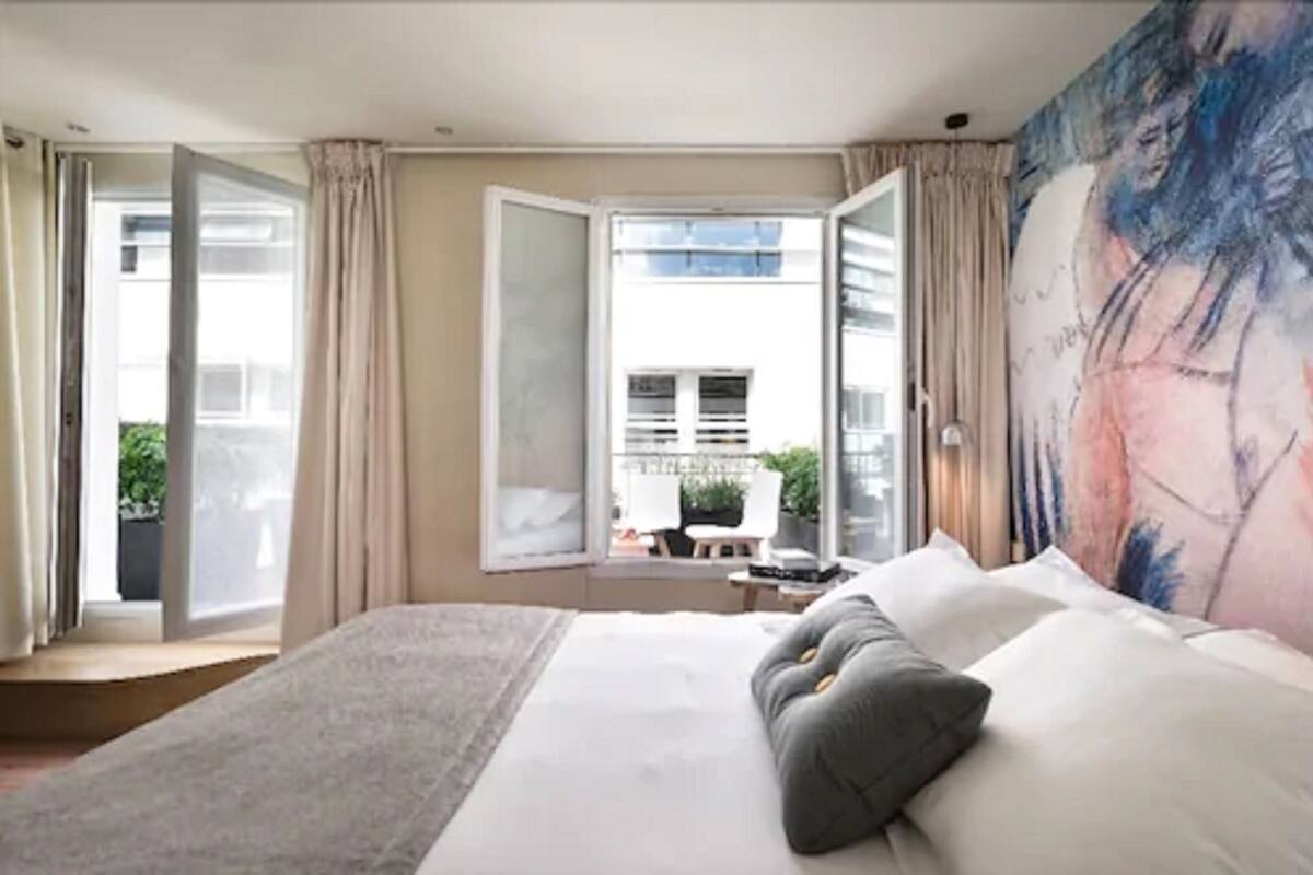 Une chambre d’hôtel moderne avec un grand lit, une vue sur l’extérieur et un tableau au mur.