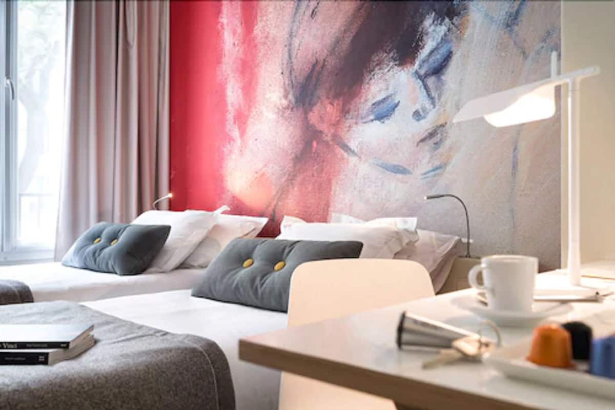 Une chambre d’hôtel avec deux lits, un bureau et une grande fenêtre.