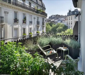 Un balcon aménagé avec du mobilier d’extérieur et des plantes en pot, offrant une vue sur le paysage urbain.