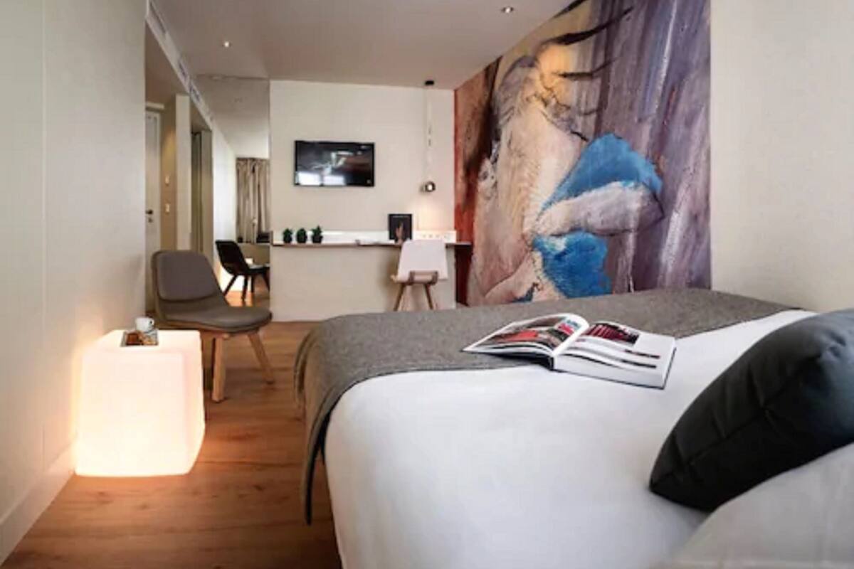 Une chambre d’hôtel avec un lit, un bureau, une chaise et un tableau au mur.