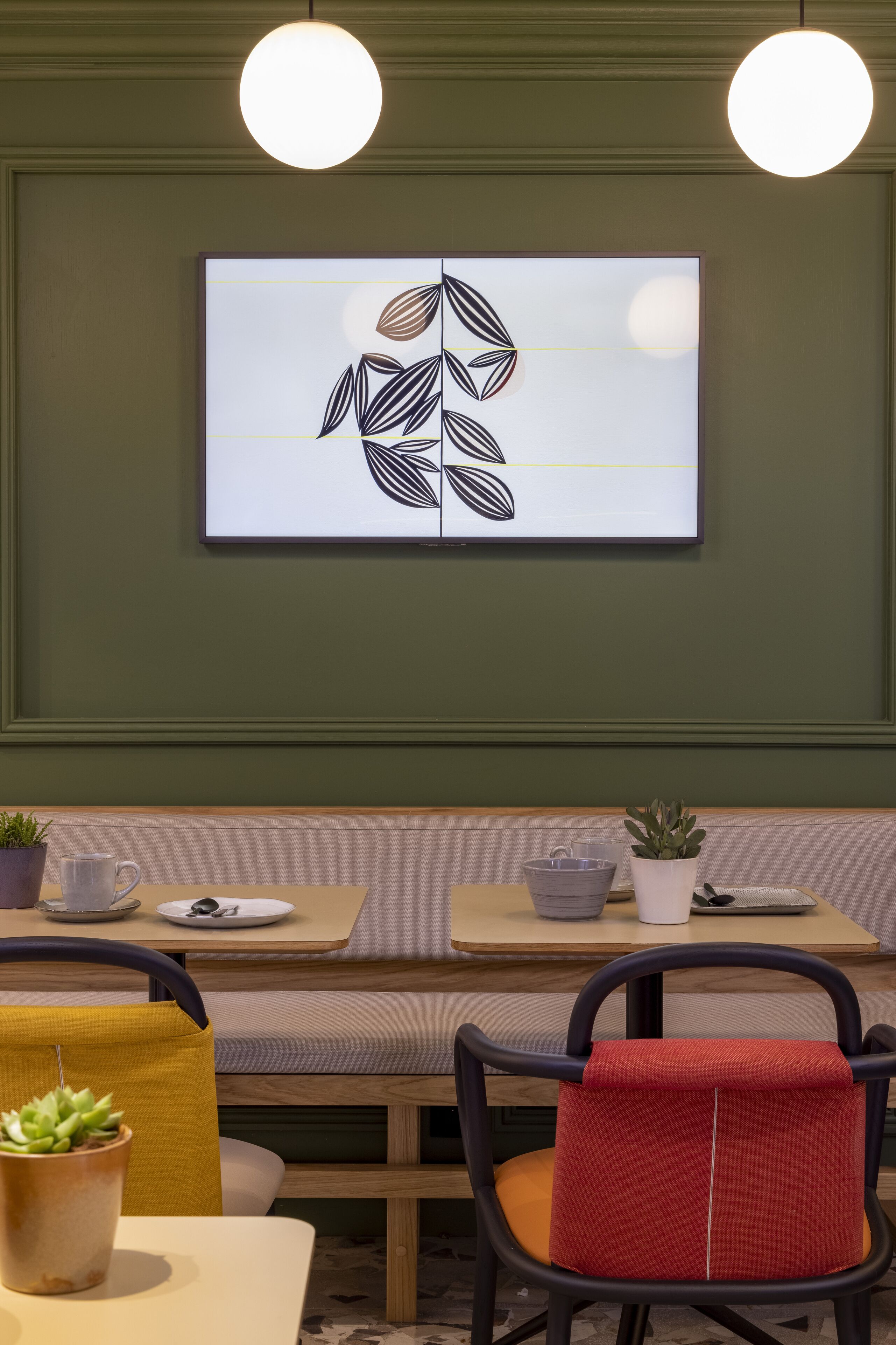 Un espace de salle à manger moderne agrémenté d’un mur vert, d’une œuvre d’art encadrée et d’un banc.