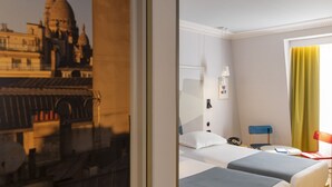 A hotel room with two beds, a desk, a chair, and a window with a view of a building. - Hotel de la Paix (Paris)