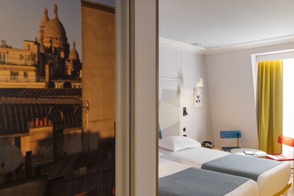 A hotel room with two beds, a desk, a chair, and a window with a view of a building. - Hotel de la Paix (Paris)