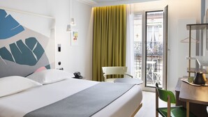 A hotel room with a bed, a chair, a table with a kettle, and a balcony with a view. - Hotel de la Paix (Paris)
