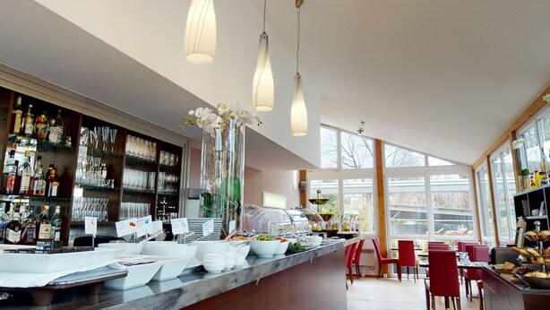 A modern restaurant with a long counter, clear glassware, and a variety of food items. - Hotel Via Roma (Salzburg)