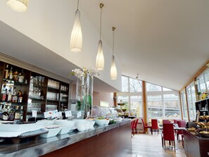 Un restaurante moderno con una barra alargada, cristalería transparente y una variedad de alimentos.