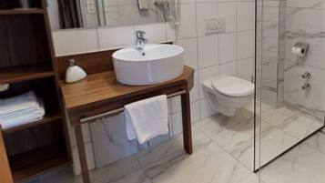 A modern bathroom with a round mirror, a sink, and a toilet.