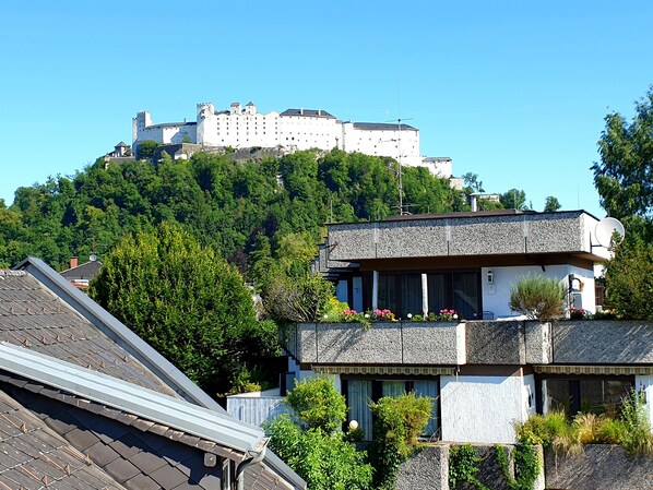 A castle on a hill with a modern building in the foreground.