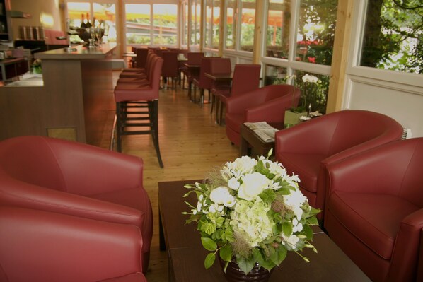 Un restaurante con sillas de cuero rojo y una mesa de madera con un centro de mesa floral.