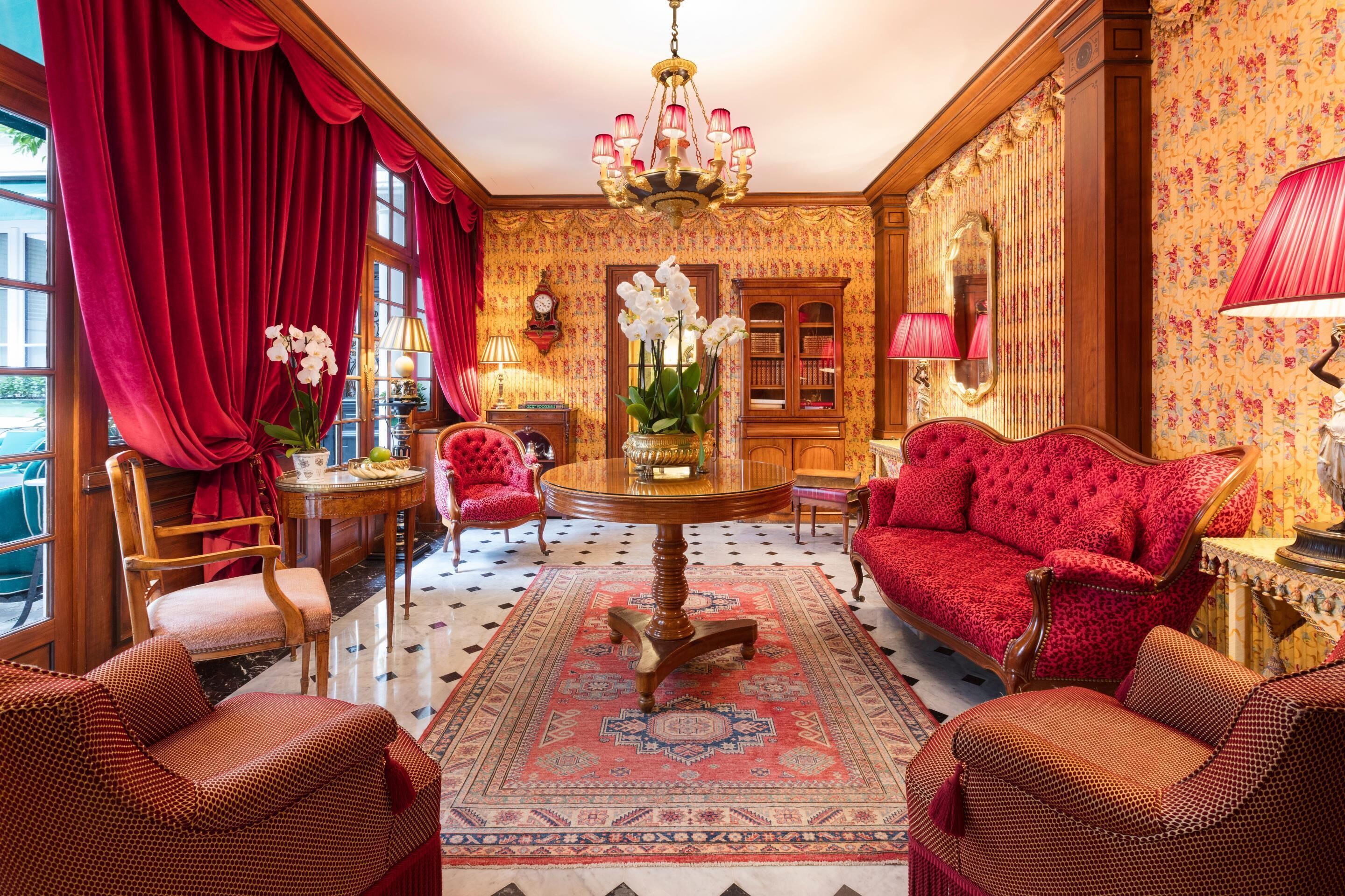 A room with a red sofa, a round wooden table, and a red armchair.