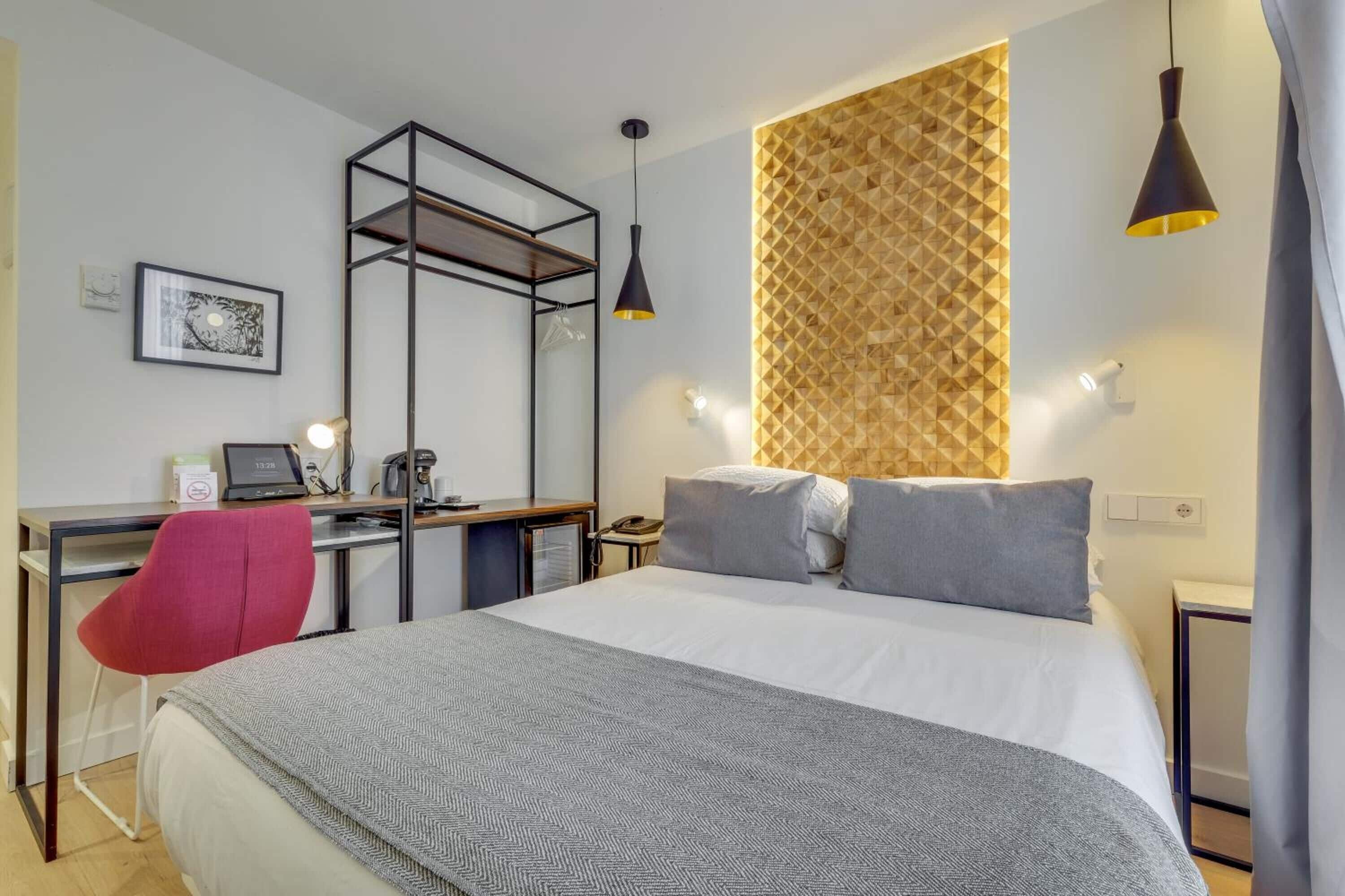 Une chambre d’hôtel avec un lit, un bureau, une chaise et une armoire.