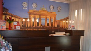 A reception desk with a large clock displaying times for Tokyo, London, Berlin, and New York. - Hotel Atlas Berlin (Berlin)