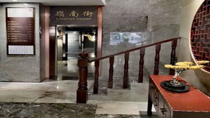 Un vestíbulo de hotel con piso de mármol, una escalera con balaustres de madera y un cartel que indica Lingnan Street.