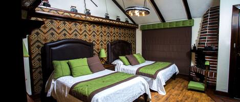 Een kamer met twee bedden, houten vloeren, een behang met patroon en een metselwerk schoorsteen.