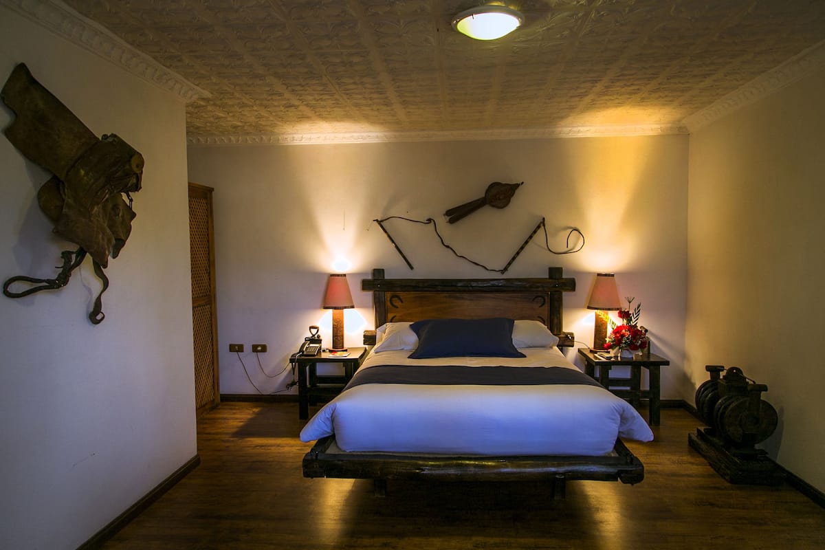 Ein Schlafzimmer mit einem hölzernen Bett, zwei Nachttischen mit Lampen, einer Wanduhr und einem Wanddekor.