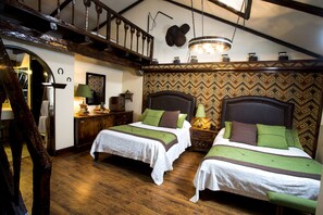 A traditional room with two beds, wooden flooring, a staircase, and a patterned wall.