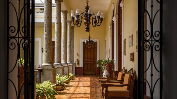 A hallway with columns, a wooden door, and a chandelier.