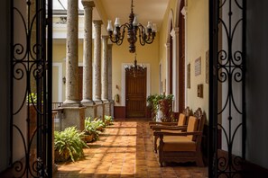 Un corridoio con colonne, una porta in legno e un lampadario.