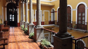 A spacious corridor with tiled flooring, large columns, and a high ceiling with a skylight.