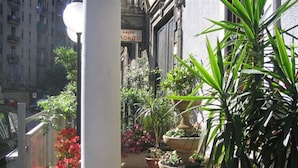 A narrow outdoor corridor with potted plants and a sign for a coffee shop. - Hotel Mayorca (Milan)