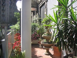 A narrow outdoor corridor with potted plants and a sign for a coffee shop.