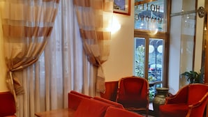 A room with a red sofa, two red armchairs, a small table, and a patterned carpet. - Hotel Mayorca (Milan)