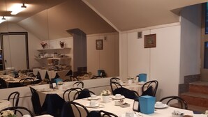 A dining area with multiple tables set for service, featuring white tablecloths, black chairs, and white tableware. - Hotel Mayorca (Milan)