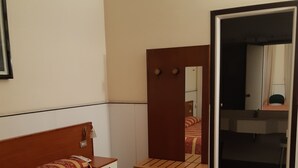 Ein Hotelzimmer mit Bett, Nachttisch, Spiegel und einer Tür zu einem Badezimmer.