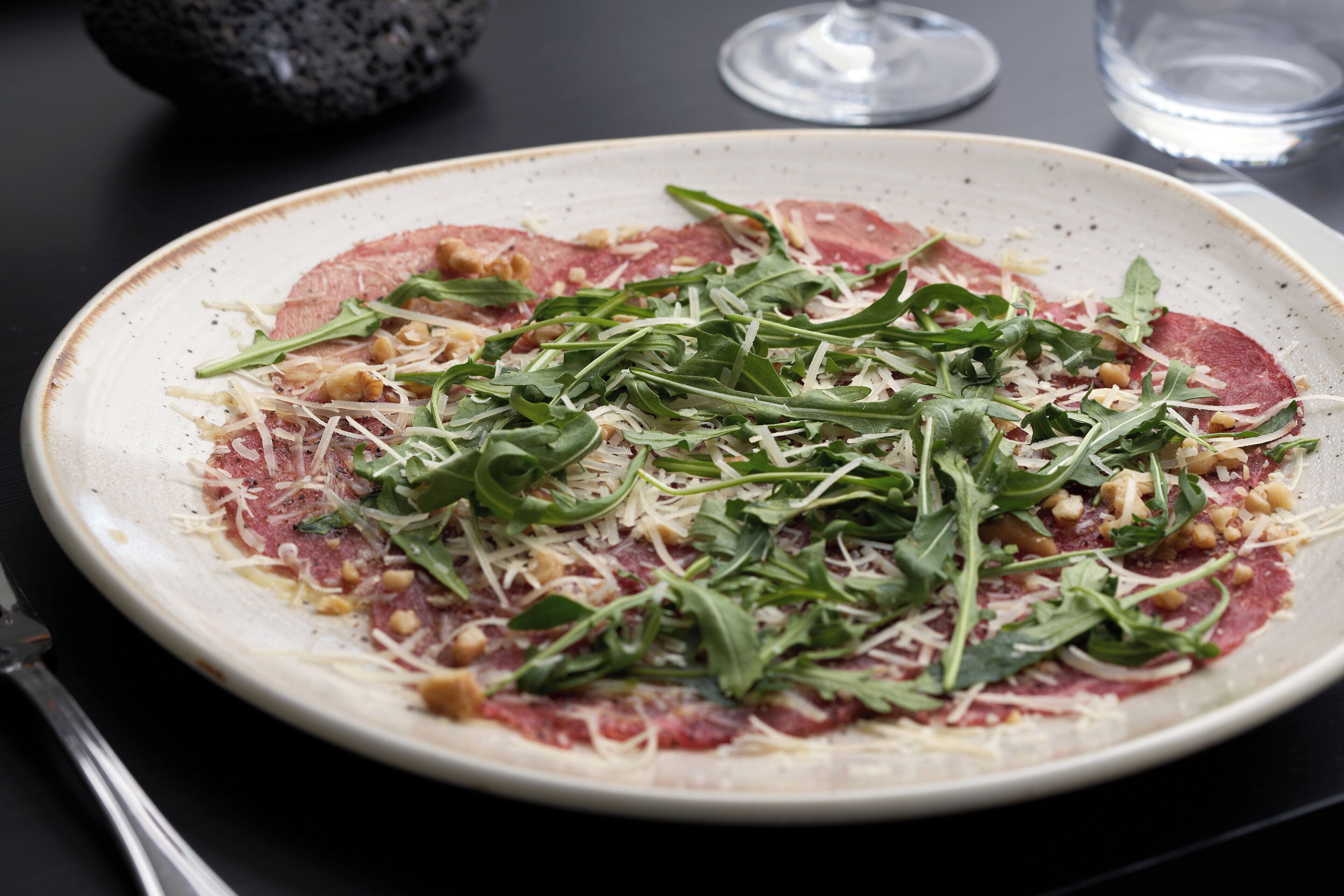 A plate of food with arugula and cheese on a ceramic plate.