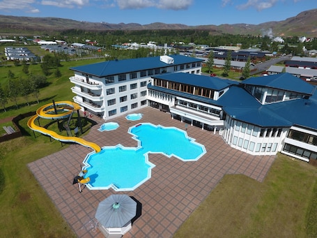 A hotel with multiple swimming pools, a water slide, and a large umbrella.