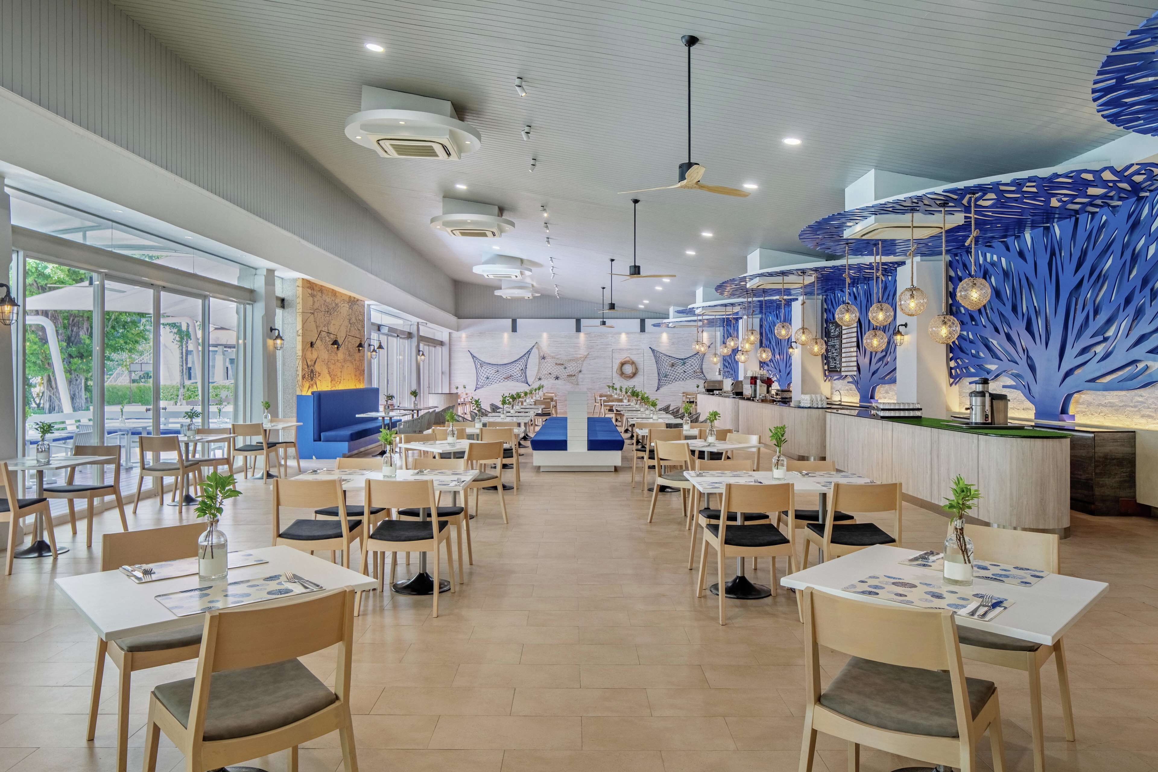 A spacious restaurant with high ceilings, modern lighting, and a central bar area.