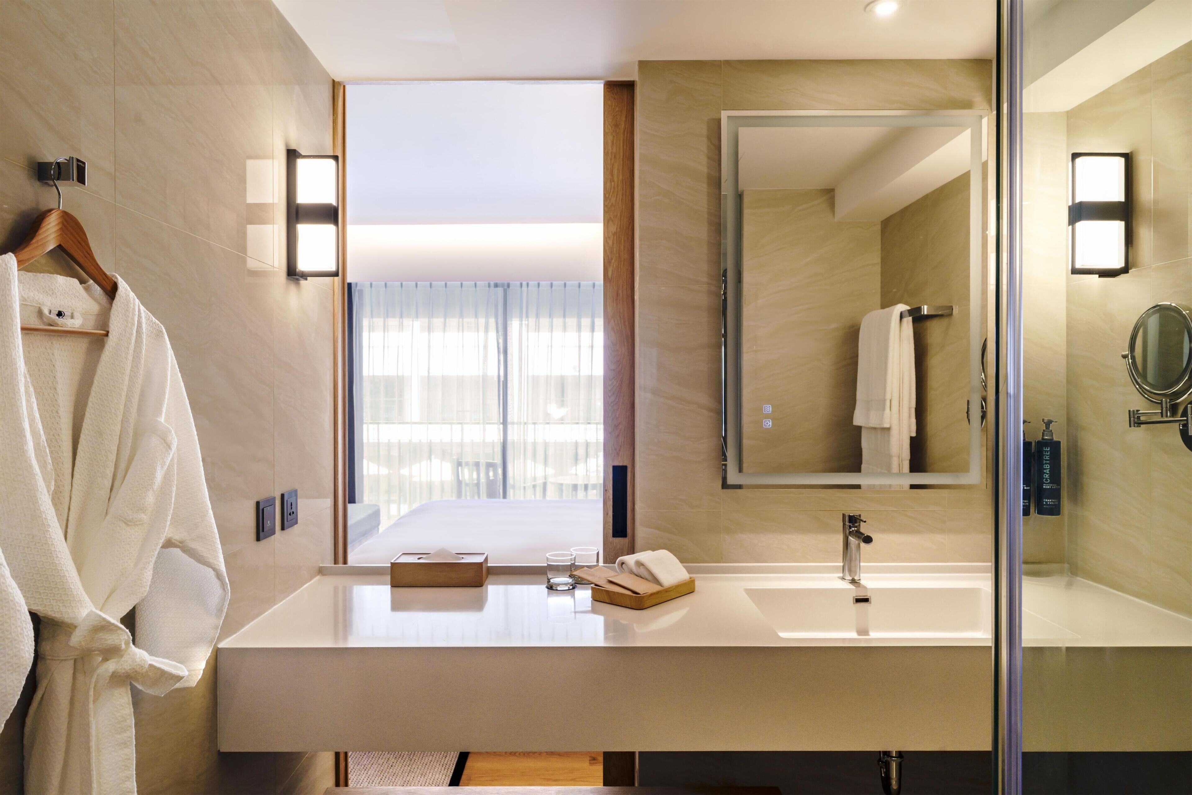 A modern bathroom with a large mirror, a sink, and a towel rack.