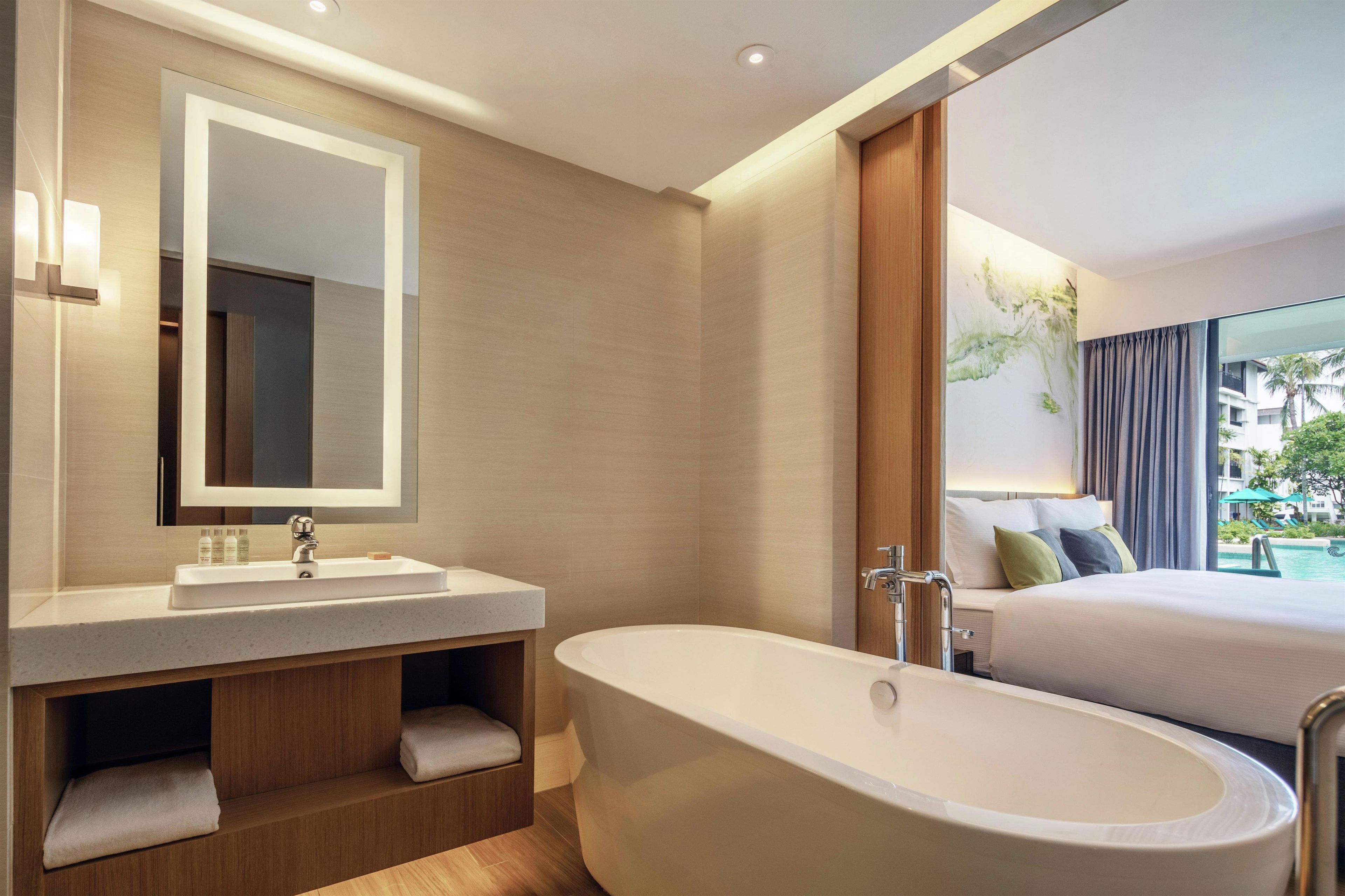 A modern bathroom with a freestanding bathtub, a large mirror, and a vanity with a sink.