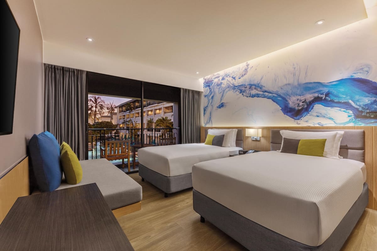 Habitación de hotel con dos camas, un sofá, un escritorio y un cuadro abstracto grande en la pared.