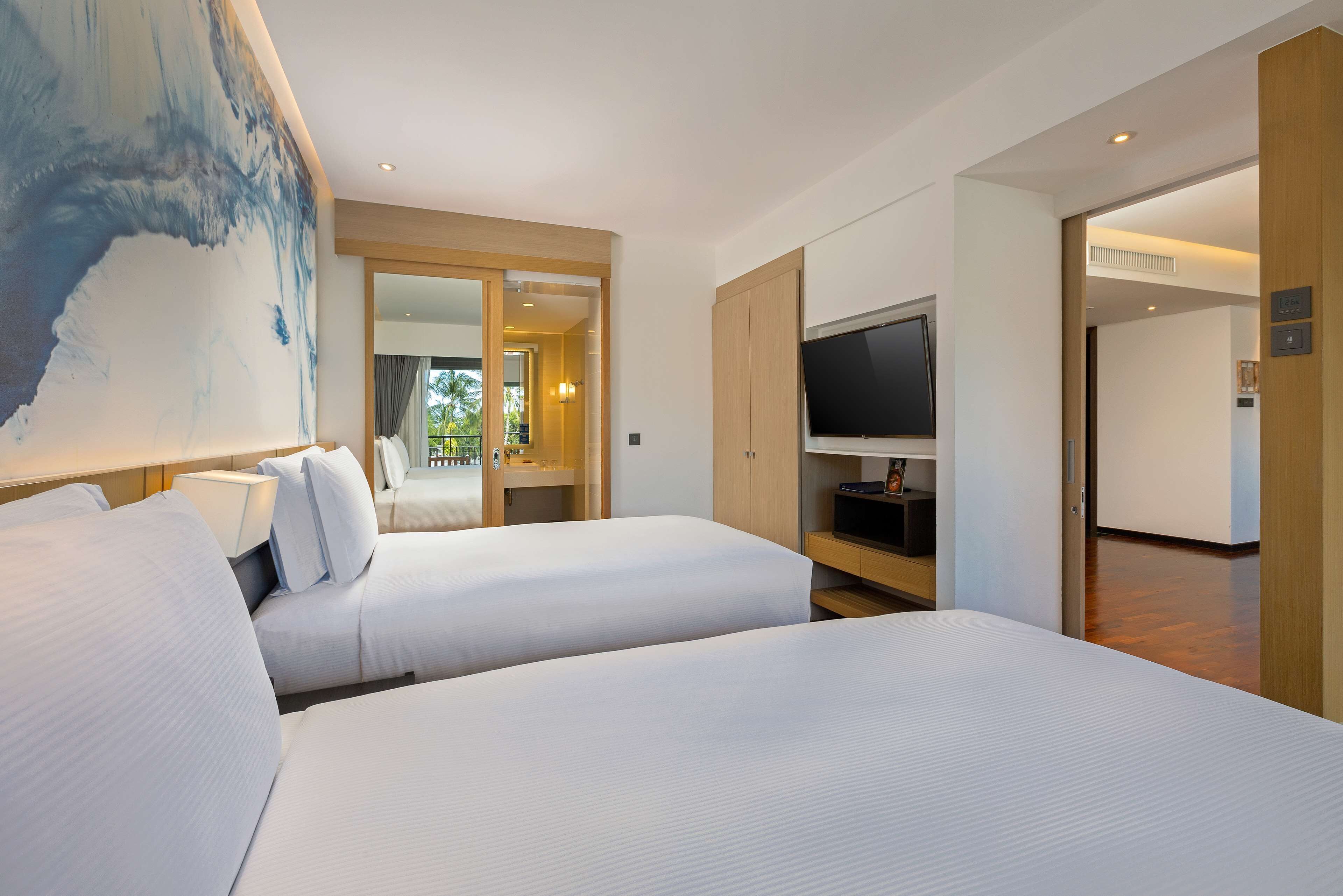 A hotel room with two beds, a TV, and a large abstract painting on the wall.