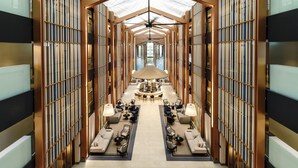 A hotel lobby with a central seating area, a bar, and bookshelves on either side.