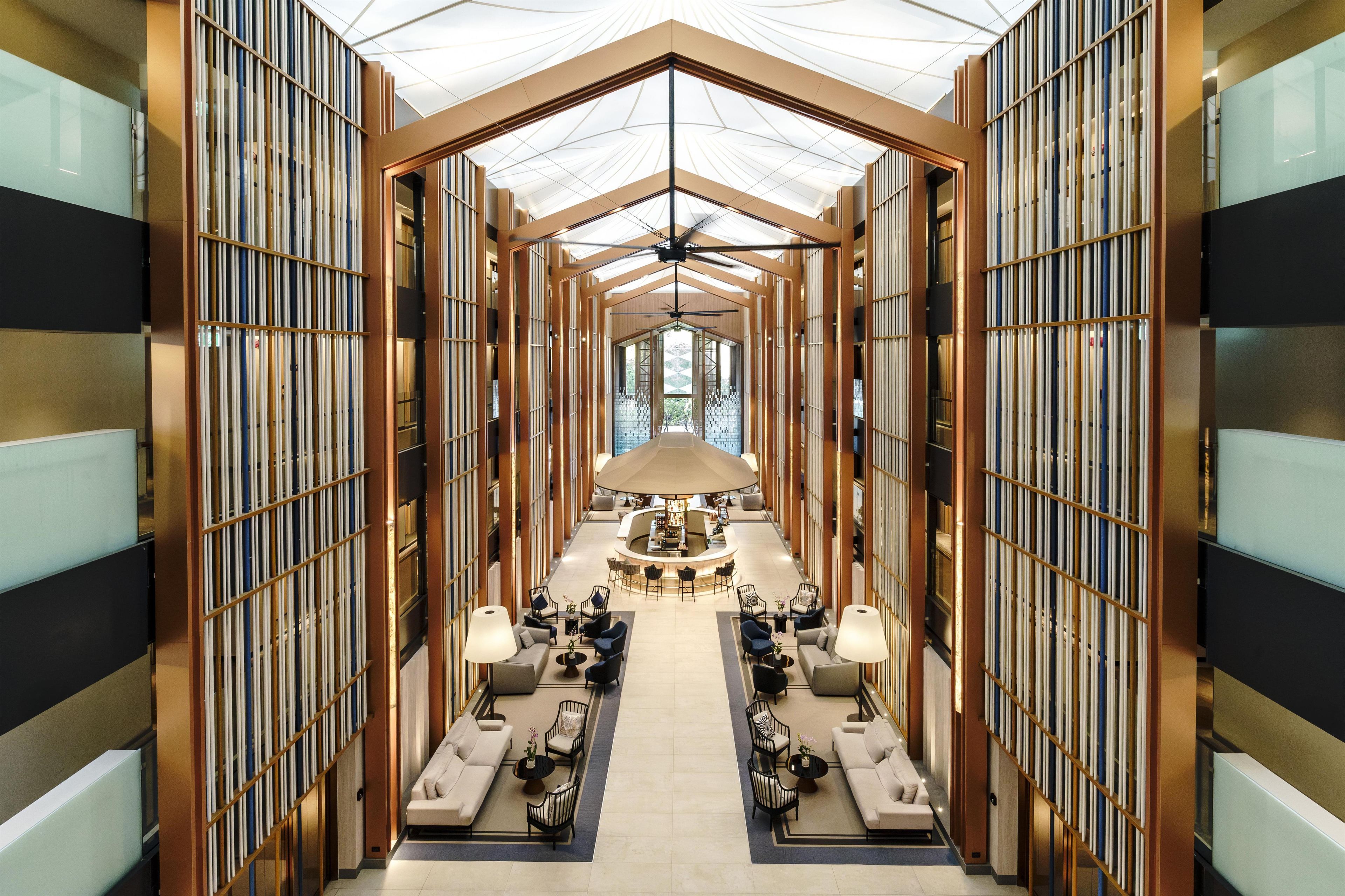 A hotel lobby with a central seating area, bookshelves on either side, and a ceiling fan.