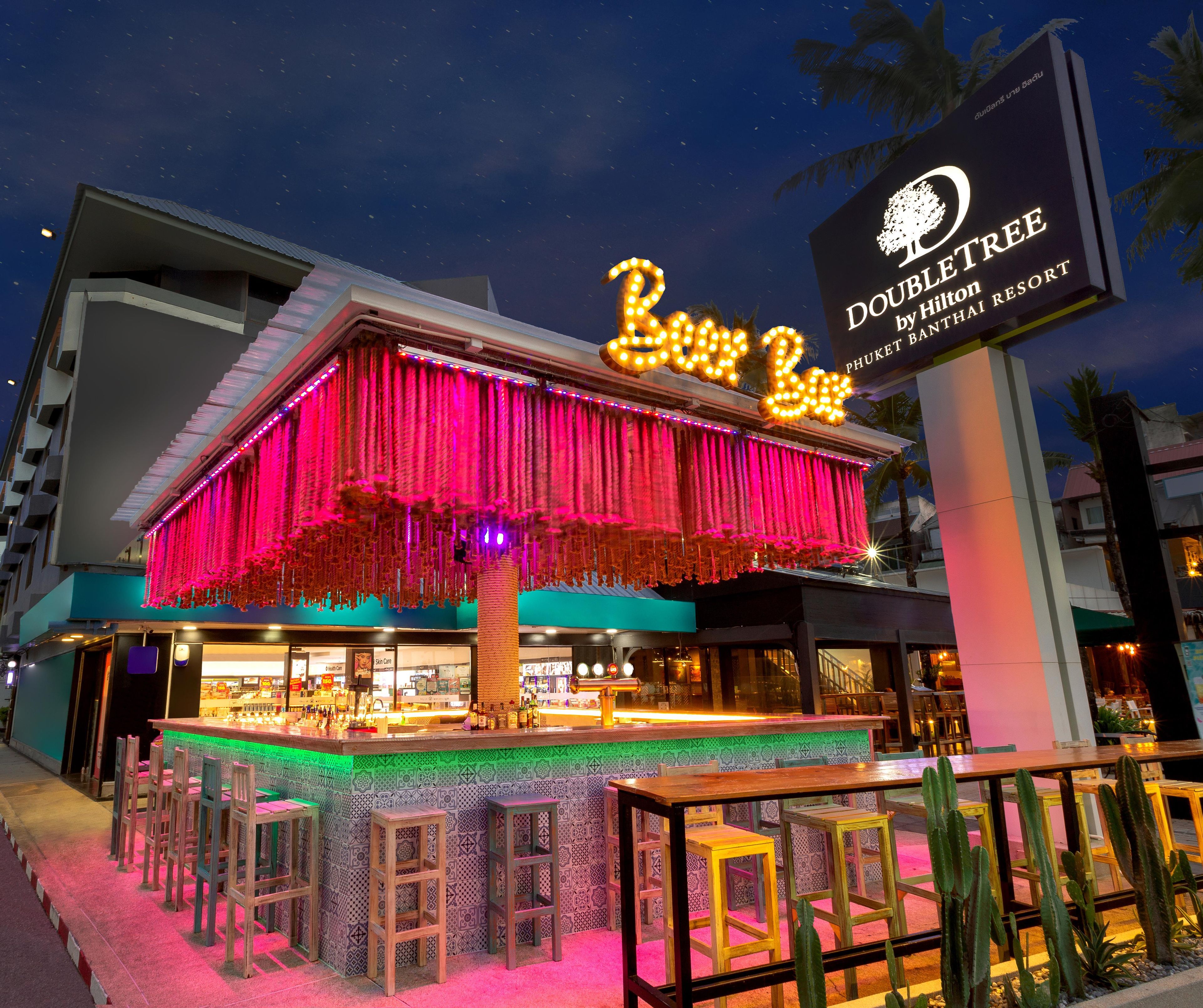 A hotel with a marquee sign, outdoor seating, and a bar area.