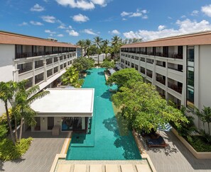 A hotel with a central swimming pool, multiple balconies, and lush greenery. - DoubleTree by Hilton Phuket Banthai Resort (Patong)