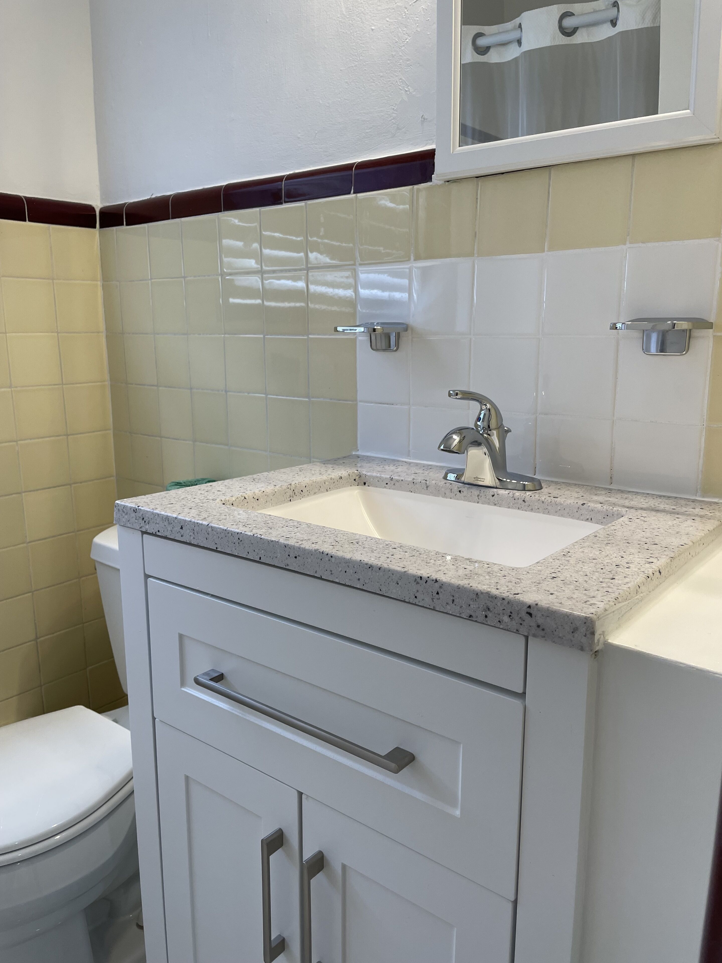 Une salle de bain avec un lavabo blanc, un miroir et des toilettes.