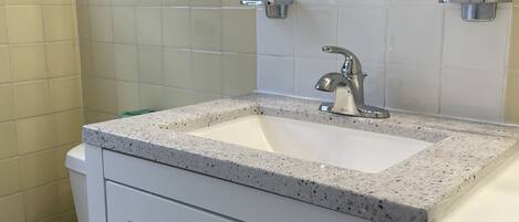 A bathroom with a white sink, a mirror, and a toilet.