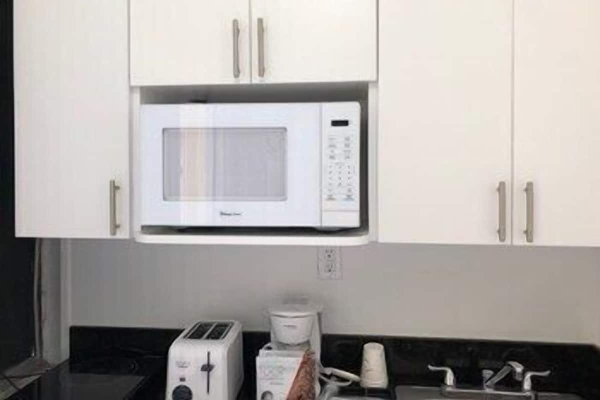 A kitchen with white cabinets, a microwave, a toaster, and a coffee maker.