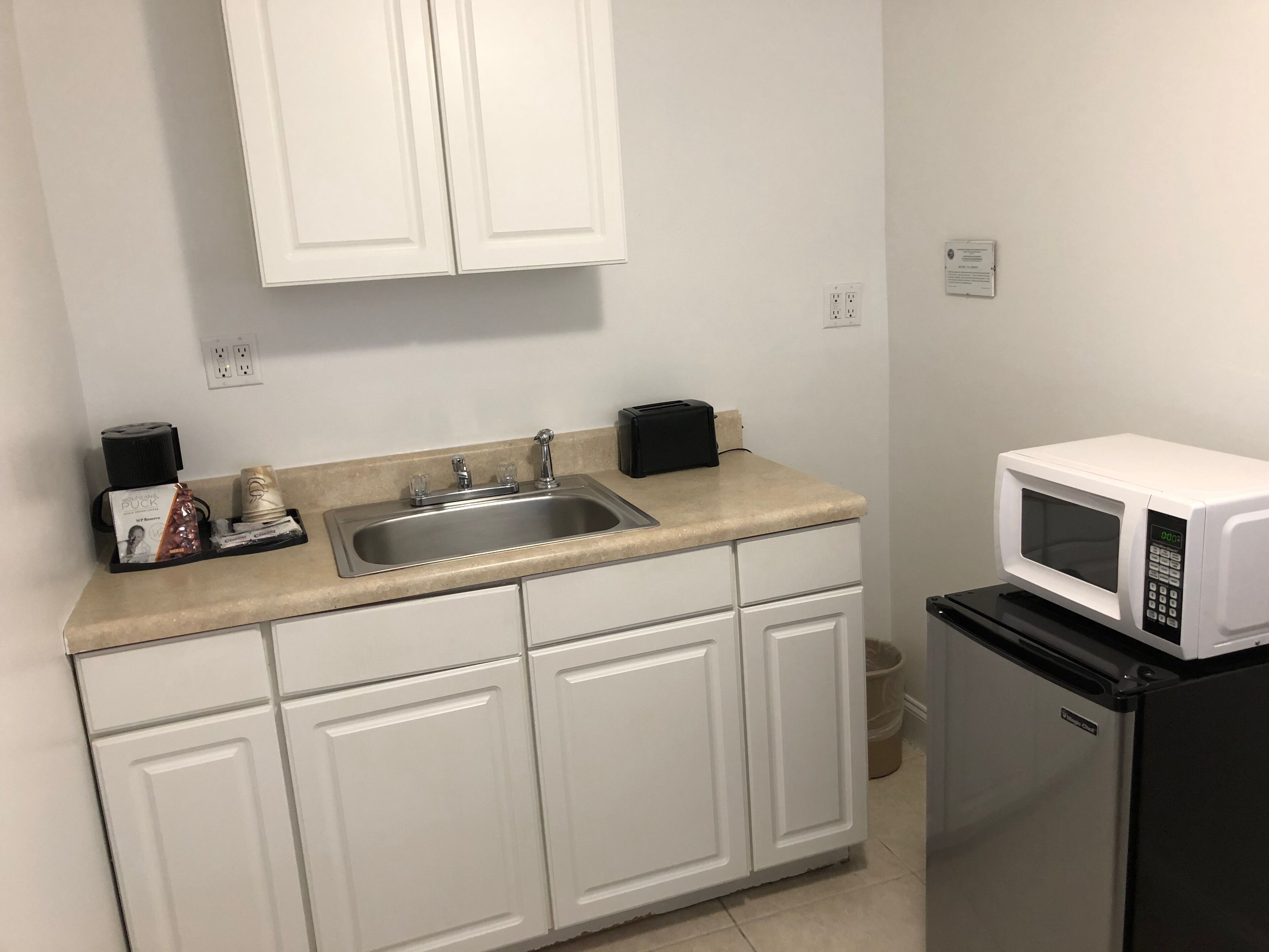 Una pequeña cocina con fregadero, microondas y refrigerador.