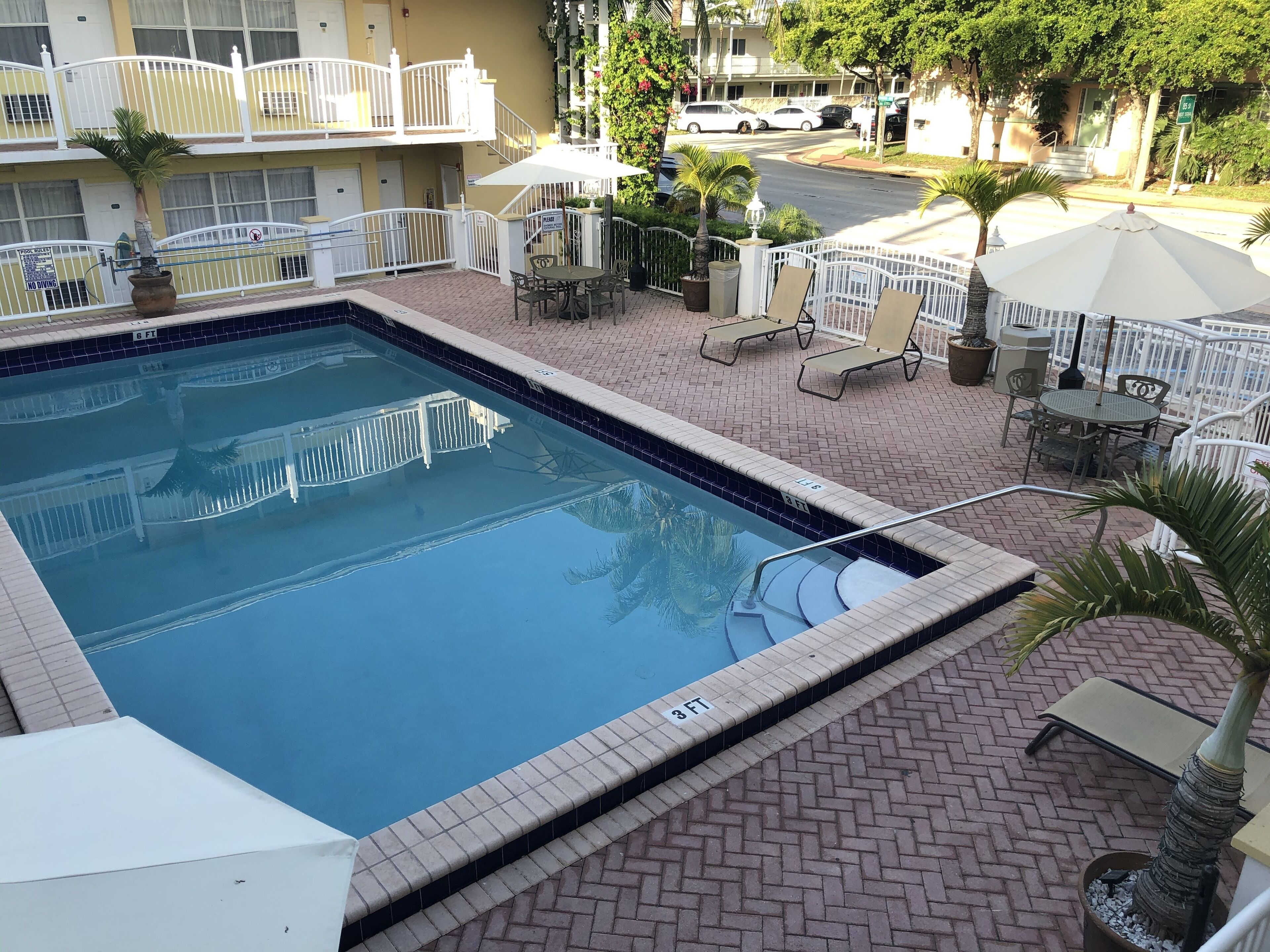 Une piscine dont le bord est revêtu de carreaux, entourée d’une terrasse en briques avec des chaises longues et des parasols.